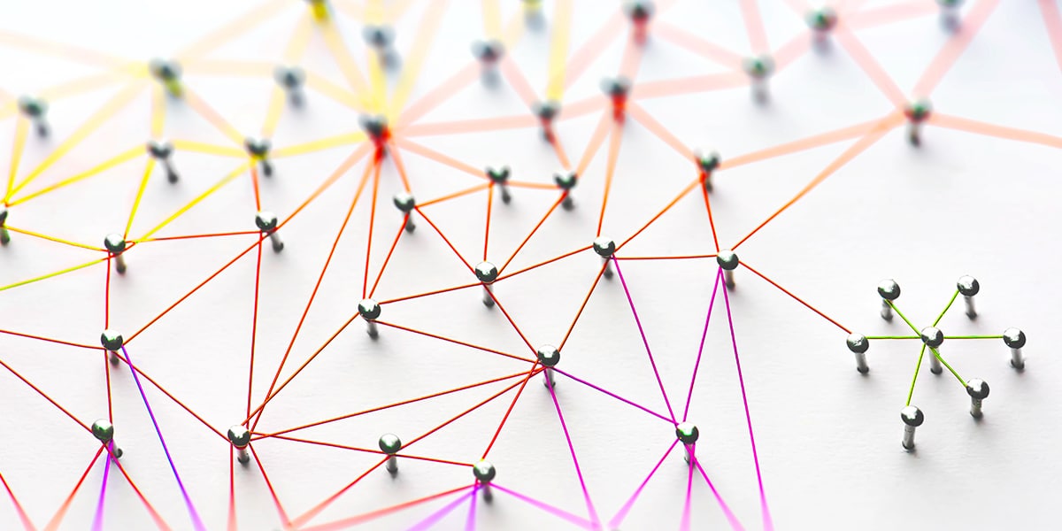 Photograph of pins connected by multicolored strings to represent a network of organizations