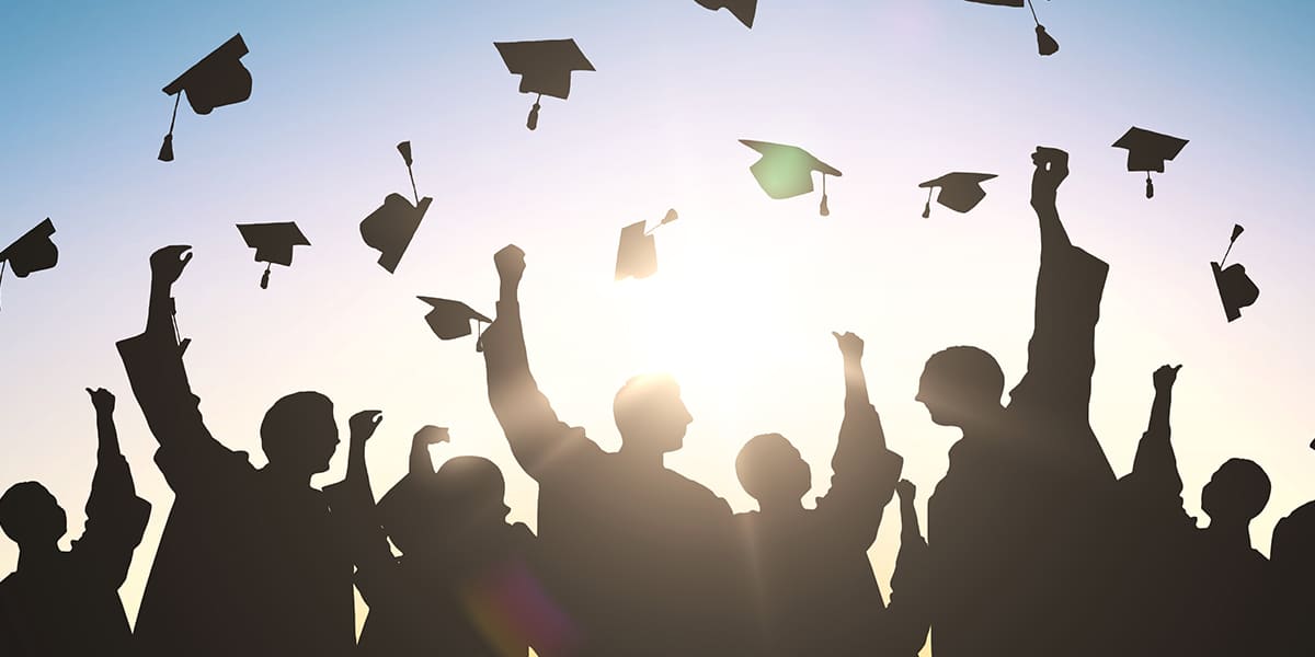 Photograph of students tossing their caps at graduation
