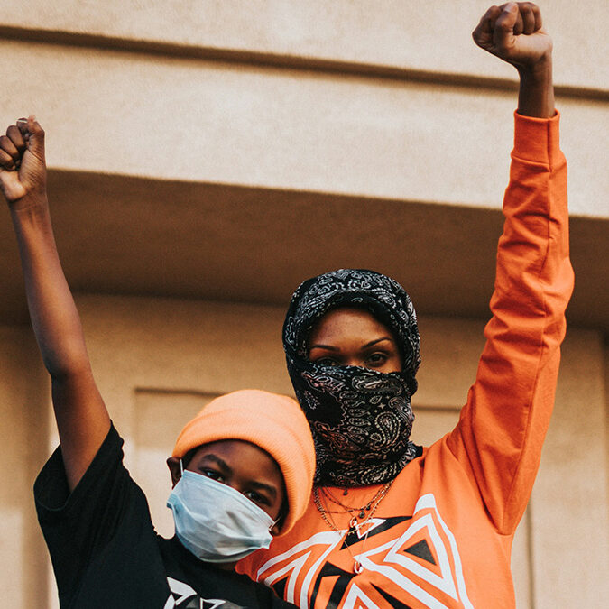 Photograph of two women with their fist raised